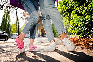 Cropped portrait of two girls legs wear jeans posing new shoes collection sunny weather street outside