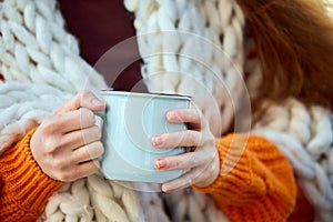 Cropped portrait of young girl covered blanket holding warming hot cup of coffee, tea or hot chocolate. Autumn mood.