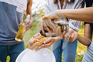 Cropped portrait of young people cooking junk food for picnic together on warm summer day
