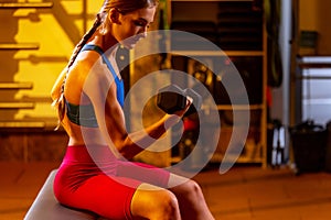 Cropped portrait of young woman training, pumping hands with dumbbells in gym. Healthy and sportive ligestyle