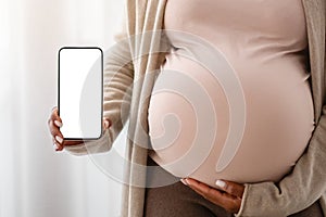 Cropped of pregnant black woman showing blank smartphone screen