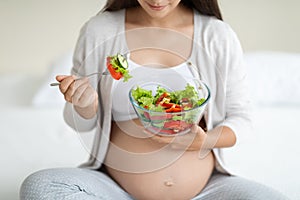 Cropped of pregnant woman eating healthy vegetable salad at home