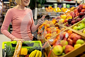 Cropped of senior woman using smartphone while shopping at supermarket