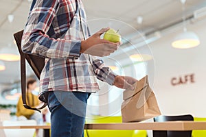 cropped shot of african american schoolboy with apple and lunch bag at school cafeteria