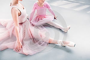 cropped shot of ballet teacher and little student stretching together