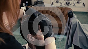 Cropped shot of barber combing hair to male client in beauty salon