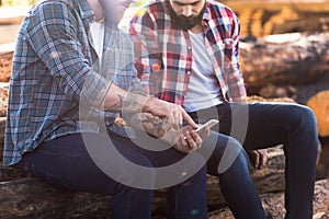 cropped shot of bearded lumberjack pointing by finger on smartphone screen to