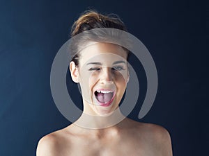 I feel like a million bucks. Cropped shot of a beautiful young woman winking against a dark background.