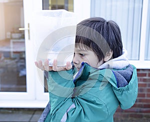 Cropped shot boy holding measuring jug pointing at level of rain collected in garden. 6 year old child measuring rainfall for