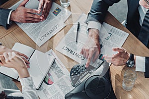 cropped shot of business people having conversation with contracts and speakerphone on table