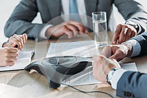 cropped shot of business people sitting around conference phone