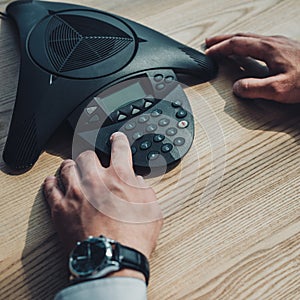 cropped shot of businessman with stylish wristwatch using speakerphone