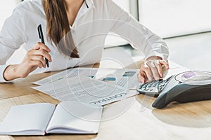 cropped shot of businesswoman with paperwork using conference phone