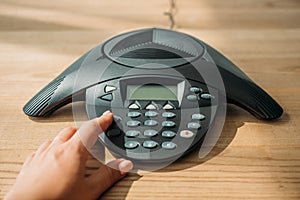 cropped shot of businesswoman with pink nails pushing button of conference phone