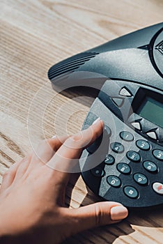 cropped shot of businesswoman with pink nails pushing button of speakerphone