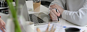 Cropped shot of businesswoman working with laptop and reading on business chart on white table