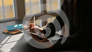 Cropped shot of  businesswomen working on digital tablet while sitting in modern office room