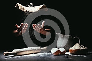 cropped shot of chef throwing up dough for pizza