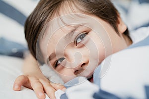 Cropped shot with Close up face kid eyes looking up, Candid shot happy boy with smiling face, Selective focus healhty child lying