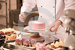 cropped shot of confectioner making cake photo