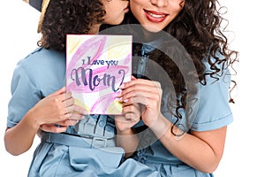 cropped shot of daughter with mothers day greeting card kissing her mother isolated on white