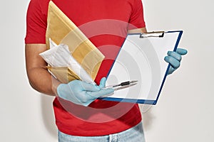 Cropped shot of delivery man holding parcels and letters, showing form for signing on clipboard, standing isolated over