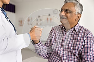 Cropped shot of doctor holding hand of senior Indian patient