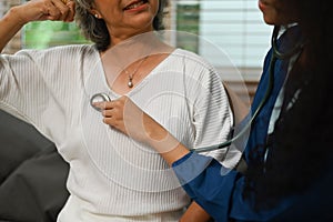 Cropped shot of doctor holding stethoscope checking lungs of elderly patient during home care visit. Elderly healthcare