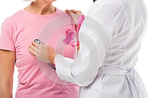 cropped shot of doctor with stethoscope checking health of senior woman with breast cancer awareness ribbon