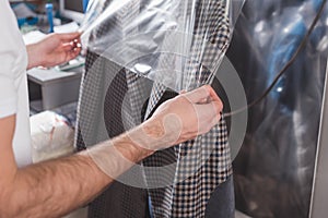 cropped shot of dry cleaning worker packing jacket