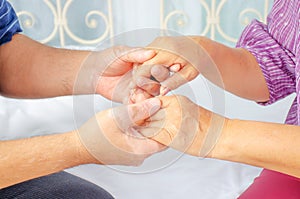 Cropped shot of elderly couple holding hands while sitting together at home, Concept of take care together, Focus on hands