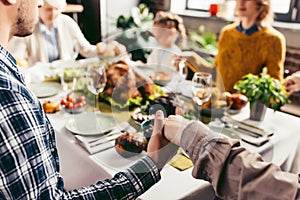 cropped shot of family holding hands and praying on thanksgiving before