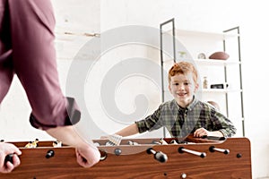 cropped shot of father and cute smiling son playing table football together