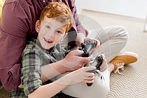 cropped shot of father and happy little son playing with joysticks