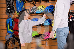 cropped shot of father and smiling son choosing bicycle helmets in bike