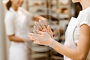 cropped shot of female baker with hands covered in flour