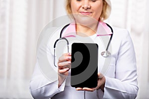 Cropped shot of a female doctor using a digital tablet, showing mock up empty screen to the camera. Selective focus on digital