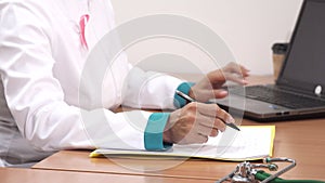 Cropped shot of a female doctor writing notes using her laptop at work