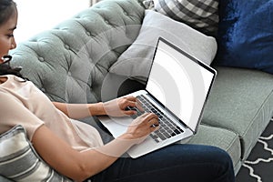 Cropped shot of female freelancer using laptop with blank screen for work on couch.