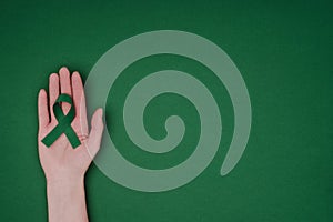 cropped shot of female hand with green awareness ribbon for Green awareness ribbon for Scoliosis, mental health symbol