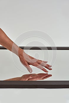 Cropped shot of female hand reaching to touch mirror reflective surface on the floor isolated over light background