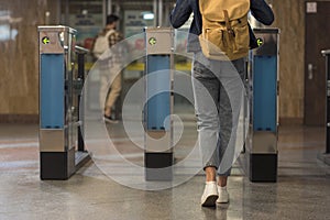 cropped shot of female stylish traveler with backpack passing through turnstiles and male