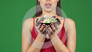 Cropped shot of a gorgeous woman licking lips holding bowl of salad