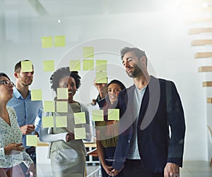 Theyve got a plan of action. Cropped shot of a group of businesspeople working on a glass wall in the office.