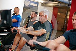 Still keeping pace with the youngsters. Cropped shot of a group of men working out on the rowing machine at the gym.