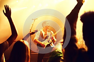 Cropped shot of a guitarist on stage surrounded by adoring fans. This concert was created for the sole purpose of this