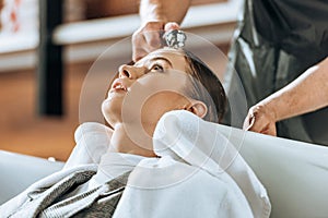 Cropped shot of hairdresser washing hair to attractive young woman