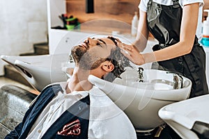 Cropped shot of hairstylist washing hair to handsome male client