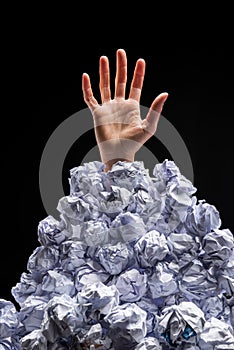 Cropped shot of hand reaching out from heap of crumpled papers