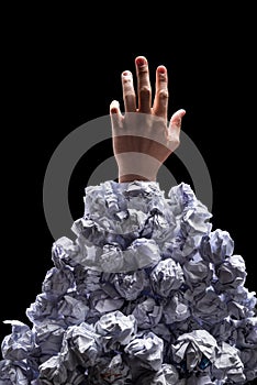 Cropped shot of hand reaching out from heap of crumpled papers